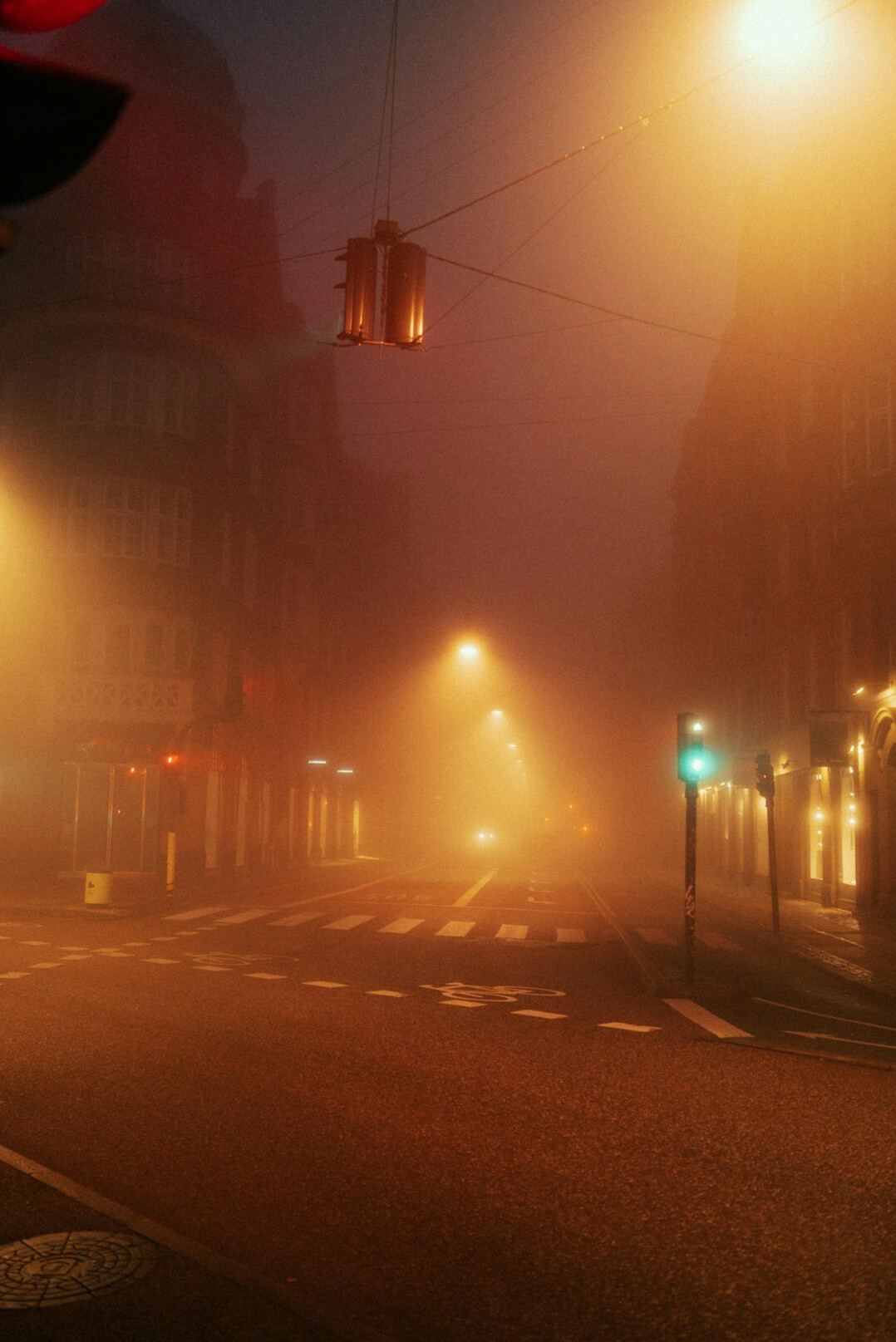 Empty city street at dusk with warm lamps and fog